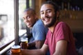 Friends, beer and chill in portrait, smile and relax indoor for fun and bonding in summer to destress. Male people, pub