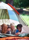 Friends, camping and happy of children in tent for resting, relaxing and bonding with cellphone. Travel gear, smile and Royalty Free Stock Photo