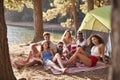 Friends camping out by a lake smiling to camera Royalty Free Stock Photo