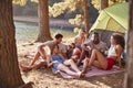 Friends on a camping trip relaxing on a blanket by a lake Royalty Free Stock Photo