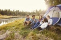 Friends on a camping trip relaxing by their tent near a lake Royalty Free Stock Photo