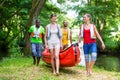 Friends carrying a canoe to river through forest Royalty Free Stock Photo