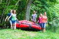 Friends carrying rubber boat to forest river