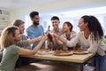 Friends Celebrating With Cheers At Home In Kitchen Eating Homemade Pizzas Royalty Free Stock Photo