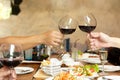 Friends celebration lunch with hands toasting glass red wine with food. Royalty Free Stock Photo