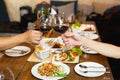 Friends celebration lunch with hands toasting glass red wine with food. Royalty Free Stock Photo