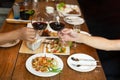 Friends celebration lunch with hands toasting glass red wine with food. Royalty Free Stock Photo