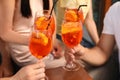 Friends clinking glasses of Aperol spritz cocktails outdoors, closeup