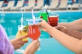 Friends clinking glasses with fresh  cocktails near swimming pool, closeup Royalty Free Stock Photo