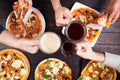 Friends clinking mugs with beer and eating pizza. Top view on ma Royalty Free Stock Photo