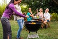 Friends cooking food on grill. Outdoor garden barbecue party. Friends laughing and having fun, enjoying wine in backyard Royalty Free Stock Photo