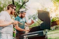 Two friends cooking on grill during summertime. Portrait of men grilling and having a garden barbecue party Royalty Free Stock Photo