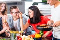 Friends cooking pasta and meat in domestic kitchen