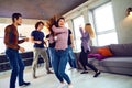 Friends dance at a student`s party in the apartment.
