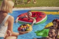 Friends eating fruit while having fun at the swimming pool Royalty Free Stock Photo