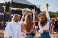 Group of women with colorful drinks at beach festival, arms raised in celebration during summer music event. Friends Royalty Free Stock Photo