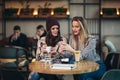 Friends enjoying coffee together in a coffee shop and using phone Royalty Free Stock Photo