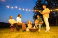 Friends Enjoying a Fireside Guitar Session Under String Lights Royalty Free Stock Photo