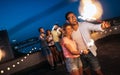 Friends enjoying a rooftop party and dancing with sparklers