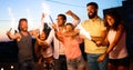 Friends enjoying a rooftop party and dancing with sparklers