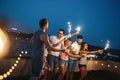 Friends enjoying rooftop party with sparklers Royalty Free Stock Photo