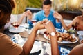 Friends, food and praying hands for group faith, Christmas or thanksgiving lunch and wine at table. People with religion