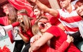 Friends football supporter fans hugging each other watching soccer match event at stadium - Young people group with red Royalty Free Stock Photo