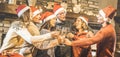 Friends group with santa hats celebrating Christmas with champagne wine toast at home dinner - Winter holidays concept