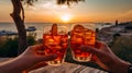 friends hand cheers with aperol splash in glass on front sunset beach and sea, bokeh sun flares