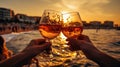 friends hand cheers with wine splash in glass on front sunset beach and sea, bokeh sun flares