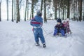 Friends have fun in wonderland, little boy pulls a sledge with sibling across winter forest Royalty Free Stock Photo