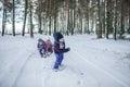 Friends have fun in wonderland, little boy pulls a sledge with sibling across winter forest Royalty Free Stock Photo