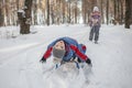 Friends have fun in wonderland, little girl pulls a sledge with brother across winter forest Royalty Free Stock Photo