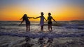 Friends having fun splashing ocean waves on beach at sunset Royalty Free Stock Photo