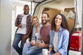 Friends Helping Couple To Unload Removal Truck On Moving Day