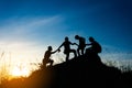 friends helping each other and with teamwork trying to reach the top of the mountains during wonderful summer sunset