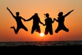 Friends jumping in sunset at beach Royalty Free Stock Photo