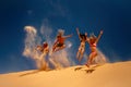 Friends jumping on the yellow sand dune. Royalty Free Stock Photo