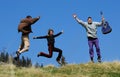 Friends jumps over a grass field on mountain