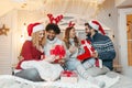 Friends on a large bed, exchanging Christmas presents; enjoying, happy Royalty Free Stock Photo