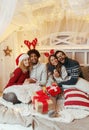 Friends on a large bed, exchanging Christmas presents; enjoying, happy Royalty Free Stock Photo