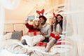 Friends on a large bed, exchanging Christmas presents; enjoying, happy Royalty Free Stock Photo