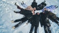 Friends lie in the snow on their backs in a circle shape. Royalty Free Stock Photo