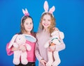 Friends little girls with bunny ears celebrate Easter. Children with bunny toys on blue background. Sisters smiling cute