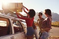 Friends Loading Luggage Onto Car Roof Rack Ready For Road Trip Royalty Free Stock Photo