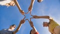 Friends make a star shape from their hands against a blue sky