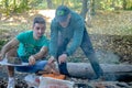 Friends making barbecue outdoors in woods.