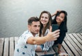 Friends making selfie sitting on pier with lake background while Royalty Free Stock Photo