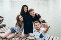 Friends making selfie sitting on pier with lake background while Royalty Free Stock Photo