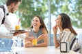 Friends meeting in a bar with a waiter serving Royalty Free Stock Photo